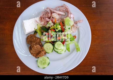 Salade de concombre avec oignon, chou, fromage feta et falafel dans une assiette blanche sur la table. Salade méditerranéenne fraîche salade arabe avec des ingrédients frais Banque D'Images