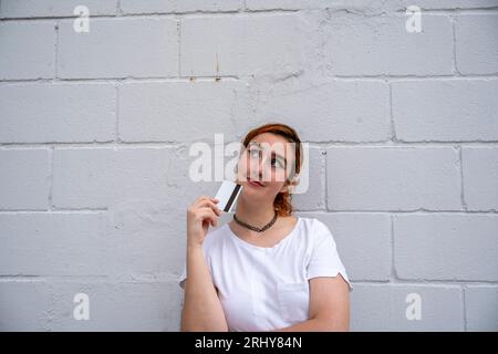 Jeune femme souriante debout près du mur avec carte de crédit Banque D'Images