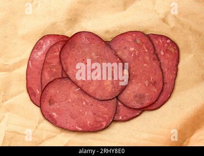 Prosciutto tranché sur papier alimentaire vue de dessus. Veau aux épices savoureux en-cas. Saucisse de veau finement tranchée. Fines tranches de jambon séché Banque D'Images