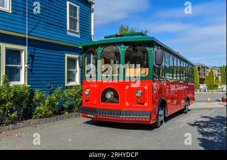 Red Tour bus - Une vue matinale ensoleillée d'automne d'un bus local rouge-vert vif du tramway d'Oli le stationnant dans une ruelle à Bar Harbor, Maine, États-Unis. Banque D'Images