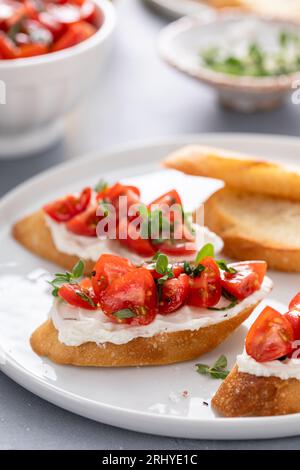 Bruschettas de tomates au basilic et au fromage à la crème avec tomates cerises fraîches et herbes Banque D'Images