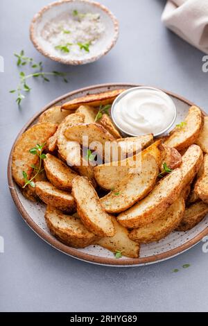 Quartiers de pommes de terre cuits au four avec des herbes et du parmesan servis avec une sauce trempette Banque D'Images