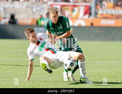 Augsbourg, Allemagne. 19 août 2023. Elvis Rexhbecaj (à gauche) d’Augsbourg affronte Robin Hack de Moenchengladbach lors du match de football allemand de première division Bundesliga entre le FC Augsbourg et le Borussia Moenchengladbach à Augsbourg, en Allemagne, le 19 août 2023. Crédit : Philippe Ruiz/Xinhua/Alamy Live News Banque D'Images