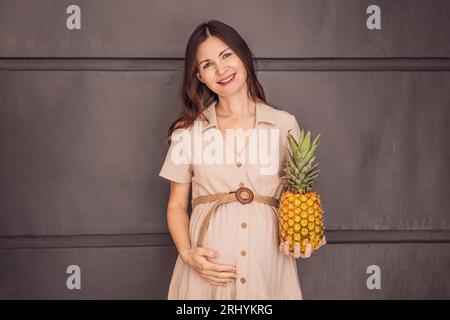 Le ventre d'une femme enceinte, présentant magnifiquement la taille de son bébé, ressemblait à un ananas. Explorez les avantages et les inconvénients potentiels de l'ananas Banque D'Images