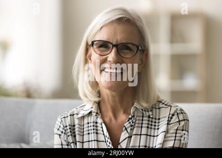 Femme mûre blonde joyeuse dans des lunettes à la mode et chemise décontractée Banque D'Images