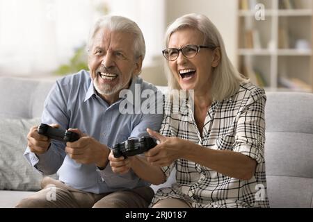 Joyeux couple senior excité jouant au jeu vidéo en ligne Banque D'Images