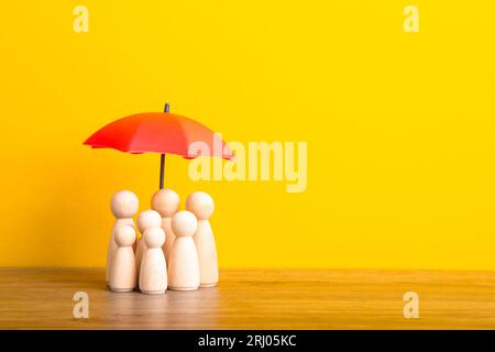 Parapluie et figurines de poupée en bois. Concept de couverture d'assurance. Banque D'Images