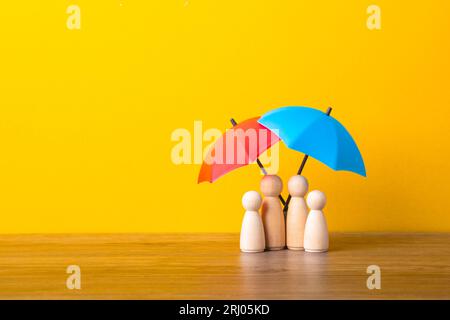 Parapluie et figurines de poupée en bois. Concept de couverture d'assurance. Banque D'Images