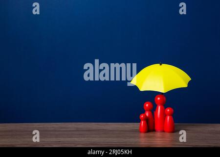 Parapluie et figurines de poupée en bois. Concept de couverture d'assurance. Banque D'Images