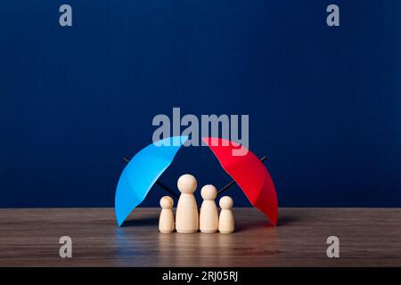 Parapluie et figurines de poupée en bois. Concept de couverture d'assurance. Banque D'Images