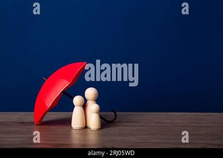 Parapluie et figurines de poupée en bois. Concept de couverture d'assurance. Banque D'Images