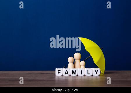 Parapluie et figurines de poupée en bois. Concept de couverture d'assurance. Banque D'Images