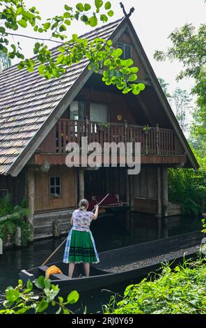 Burg, Allemagne. 20 août 2023. Une femme en costume traditionnel sorabe-wenish voyage sur une barge en bois sur une rivière (voie navigable) dans le Spreewald. Crédit : Patrick Pleul/dpa/Alamy Live News Banque D'Images