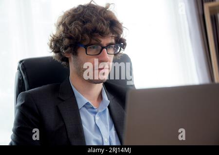 Jeune homme d'affaires caucasien utilisant la planification d'ordinateur portable pour le succès dans le bureau moderne, homme d'affaires tapant sur ordinateur portable avec confiant, exécutif ou M. Banque D'Images