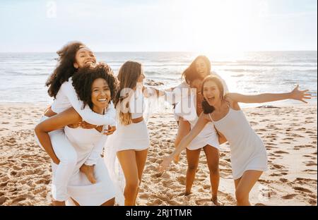 Des dames ludiques et diverses se cognent les unes les autres sur la plage, ayant une fête de poule et des dupes autour, espace de copie Banque D'Images