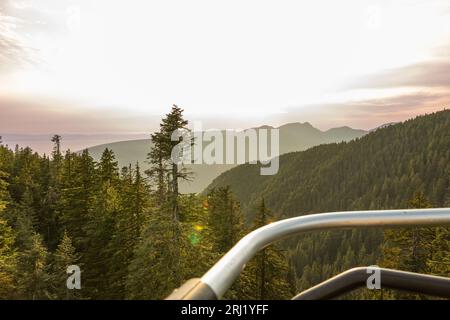 Vue panoramique sur le coucher du soleil depuis le télésiège, capturant la beauté de Grouse Mountain avec Burrard Inlet visible Banque D'Images