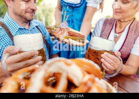 Serveur apportant de la nourriture au couple dans le jardin de bière Banque D'Images