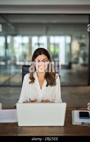Heureuse femme d'affaires mature ayant réunion hybride dans le bureau, vertical. Banque D'Images