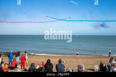 Les gens regardent depuis la plage tandis que l'équipe de renommée mondiale de la RAF expose les Red Arrows se produire le long du front de mer lors de l'exposition annuelle Eastbourne Airbourne, une Inte Banque D'Images