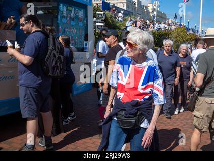 Une femme âgée portant un T-shirt drapeau Union Jack marche dans la foule le long de la promenade sur le front de mer d'Eastbourne alors qu'ils assistent à l'Eastbourne Air annuel Banque D'Images