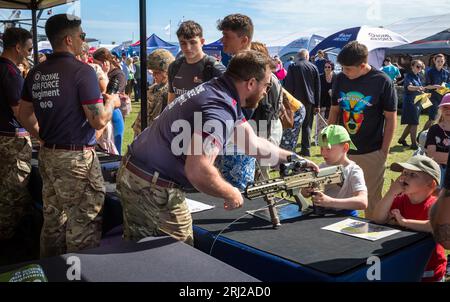 Un jeune garçon est montré un fusil d'assaut militaire SA80 par un soldat du régiment de la RAF sur un stand dans l'exposition militaire à côté de l'annu Banque D'Images