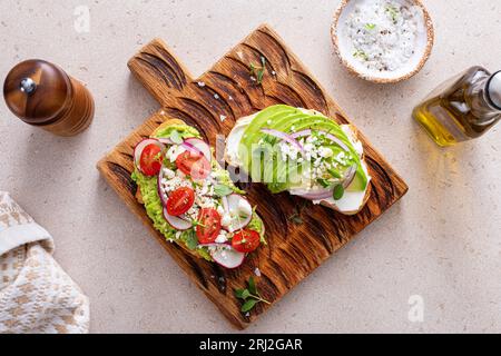 Toasts d'avocat avec radis, tomates et feta garnis d'huile d'olive, idée de petit déjeuner sain Banque D'Images