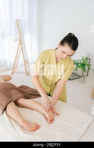 Portrait vertical d'une femme médecin professionnelle faisant de la gymnastique et du massage des pieds à un garçon de cinq ans. Vue de dessus de la masseuse préformant la jambe orthopédique Banque D'Images