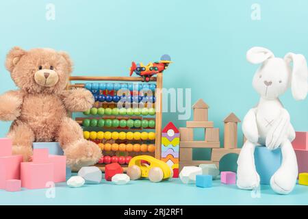 Collection de jouets pour enfants avec ours en peluche, lapin blanc, abaque en bois et blocs pour jeux d'enfants. Jouets éducatifs colorés pour bébés sur bleu clair Banque D'Images