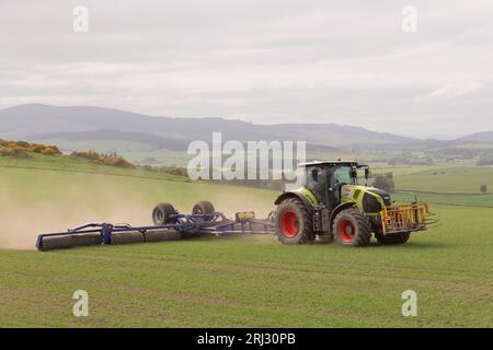 Rouler une récolte d'orge de printemps dans la campagne de l'Aberdeenshire avec un tracteur Claas Axion 850 et des rouleaux Dal-Bo Power-Roll 1530 Banque D'Images