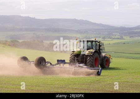 Un tracteur Claas avec Dal-Bo Power Roll 1530 Rolling un champ d'orge de printemps avec vue sur la campagne environnante de l'Aberdeenshire Banque D'Images