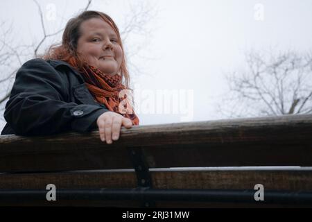 Portrait de femme souriante assise sur un banc couvert de champ contre ciel Banque D'Images