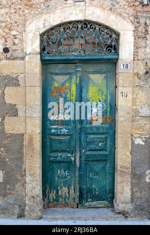 Vieille porte en bois patiné avec linteau voûté en pierre incroyable dans un ancien manoir abandonné dans la vieille ville de Rethymnon, en Crète, Grèce, Europe. Banque D'Images