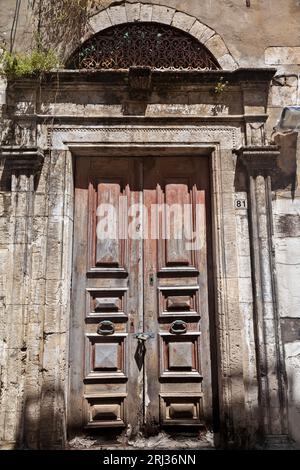 Vieille porte en bois de temps avec linteau voûté en pierre dans un ancien manoir abandonné dans la vieille ville de Rethymno, en Crète, Grèce, Europe. Banque D'Images