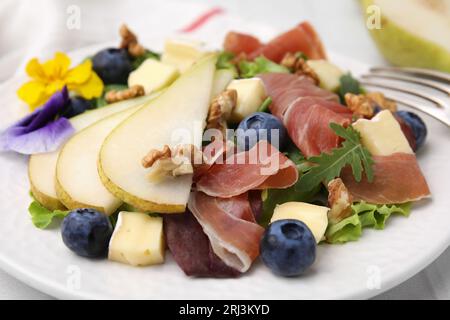 Salade savoureuse au brie, prosciutto, noix et poire sur assiette blanche, gros plan Banque D'Images