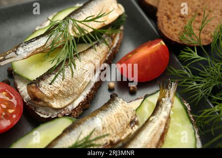 Délicieux sandwichs aux sprats, concombre et aneth servis sur assiette, gros plan Banque D'Images