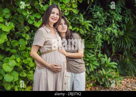 Un moment réconfortant capturé dans le parc comme une femme enceinte après 40 partage un lien spécial avec sa fille adolescente, embrassant la beauté de Banque D'Images