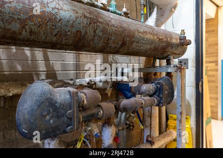 Vieille tuyauterie de soupape rouillée de corrosion, réservoir, système de chauffage HVAC à vapeur dans un bâtiment municipal. Banque D'Images