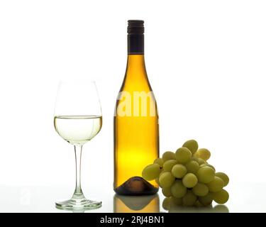 Une nature morte d'un verre de vin, d'une bouteille de vin et de raisins sur fond blanc. Banque D'Images