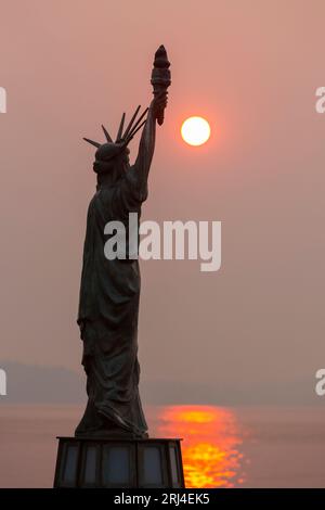 Seattle, Washington, États-Unis. 20 août 2023. Le soleil se couche sur les montagnes olympiques à travers la fumée de feu de forêt à Statue of Liberty Plaza. La qualité de l'air a considérablement diminué, car la fumée des feux de forêt dans la région a dégradé la qualité de l'air dans la ville à des niveaux insalubres. Crédit : Paul Christian Gordon/Alamy Live News Banque D'Images