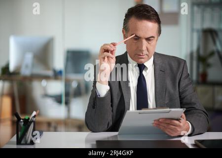 Homme d'affaires concentré relisant le document avant de signer Banque D'Images