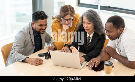 Un groupe d'hommes d'affaires professionnels ou de startups regarde un écran d'ordinateur portable, discute, planifie et brainstorming sur un nouveau projet dans The Meet Banque D'Images