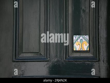 Porte en bois vert antique décorée avec un carreau de céramique émaillé majolique à Scicli Sicile, Italie. Banque D'Images