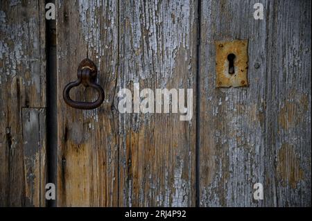 Porte en bois gris antique avec un trou de serrure rouillé et frappe en fer forgé à Scicli Sicile, Italie. Banque D'Images