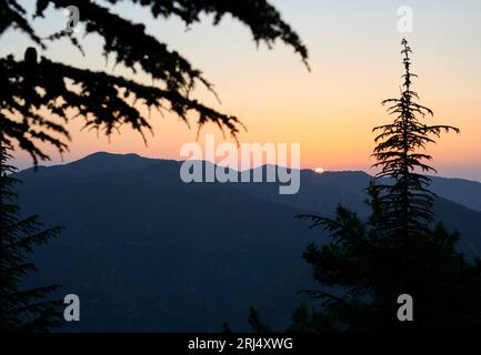 Une vue panoramique sur le coucher de soleil derrière une chaîne de montagnes verdoyantes Banque D'Images