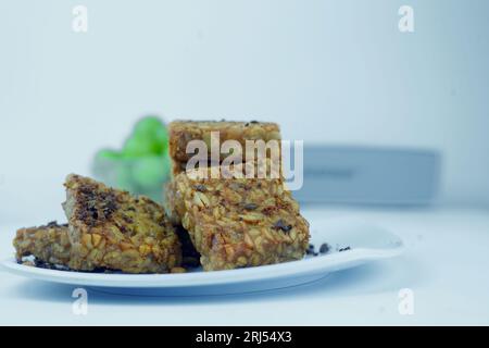 Une photo en gros plan de tempeh frit, soigneusement empilé, présenté sur une assiette blanche. Photo de nourriture isolée. Banque D'Images