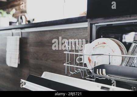 Gros plan de lave-vaisselle automatique en acier inoxydable intégré ouvert à l'intérieur de la cuisine à la maison moderne avec ustensile sale après le dîner. Ménage, ménage Banque D'Images