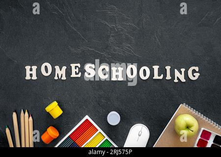 Mot homeschooling fait de lettres en bois sur un fond noir, vue de dessus. Banque D'Images