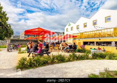 Personnes assises à l'extérieur à l'espace de co-working de Hackney Bridge, au complexe de vente au détail et au marché de la nourriture de rue, Hackney, Londres, Royaume-Uni Banque D'Images