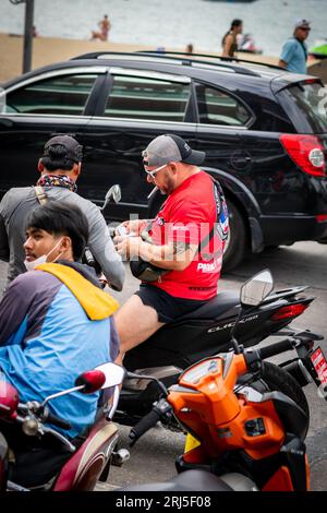 Un homme obtient son permis de conduire vérifié tout en conduisant sa moto le long de Beach Rd. Pattaya, Thaïlande. Banque D'Images