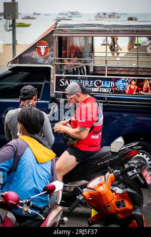 Un homme obtient son permis de conduire vérifié tout en conduisant sa moto le long de Beach Rd. Pattaya, Thaïlande. Banque D'Images